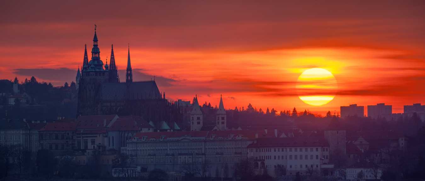 Rudý kotouč slunce za Pražským hradem